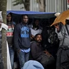 Người di cư chờ để chuyển tới trung tâm lưu trú mới sau khi cảnh sát tháo dỡ khu lán trại phía Bắc Paris. (Nguồn: EPA/TTXVN)