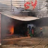 Lực lượng cứu hỏa phải phá tường để phun nước dập ngọn lửa đang bùng cháy bên trong quán karaoke Cosy. (Ảnh: Nam Thái/TTXVN)