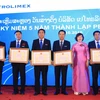 Thứ trưởng Hồ Thị Kim Thoa trao bằng khen, giấy khen cho tập thể và các cá nhân của Petrolimex Lào. (Ảnh: Phạm Kiên/Vietnam+)