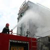 Lực lượng Cảnh sát phòng cháy chữa cháy đang nỗ lực dập lửa ngăn cháy lan sang quán karaoke, khách sạn liền kề. (Ảnh: Sỹ Tuyên/TTXVN)