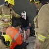 Lực lượng cứu hộ hỗ trợ người bị thương sau vụ phóng hỏa. (Nguồn: EPA/TTXVN)