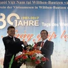 Ông Lê Thanh Hải (trái) - Bí thư thứ nhất Đại sứ quán Việt Nam tại Đức​ - tặng hoa chúc mừng tại buổi gặp mặt. (Ảnh: Thanh Bình/TTXVN)