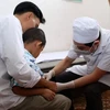 Bác sỹ Bệnh viện Da liễu Trung ương khám cho trẻ nhỏ mắc bệnh sùi mào gà. (Ảnh: Phạm Kiên/TTXVN)