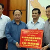 Ông Tất Thành Cang (thứ 2 từ trái sang) trao tặng bảng tượng trưng số tiền hỗ trợ cho đồng bào bị mưa lũ. (Ảnh: Phan Tuấn Anh/TTXVN)
