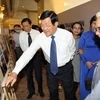 Nguyên Chủ tịch nước Trương Tấn Sang cùng phu nhân tham quan triển lãm ảnh ký sự ngoại giao tại TP.HCM. (Ảnh: Thanh Vũ/TTXVN)
