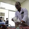 Bác sỹ Phùng Văn Hà, người trực tiếp phẫu thuật, đang kiểm tra bàn tay đã được nối lại của bệnh nhân. (Ảnh: Chu Quốc Hùng/TTXVN)