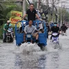Xe ba gác làm dịch vụ vận chuyển xe máy qua đoạn ngập nước tại huyện Nhà Bè. (Ảnh: Xuân Dự/TTXVN)