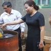 Cán bộ xã Hòa Thắng kiểm tra nguồn nước sau khi bơm lên phi đựng tại gia đình bà Sửu. (Ảnh: Phạm Cường/TTXVN)