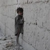 Một em bé Afghanistan đứng dựa vào bức tường khu vực đổ nát do xung đột ở ngoại ô Kabul tháng 10/2011. (Nguồn: AFP/TTXVN)