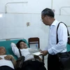 Ông Trần Công Thịnh, Tổng Lãnh sự Việt Nam tại Savannakhet, đang tặng quà và thăm hỏi các nạn nhân của vụ tai nạn. (Ảnh: Phạm Kiên/Vietnam+) 