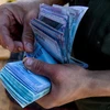 Người dân đếm tiền mệnh giá 1.000 bolivar của Venezuela để mua hàng hóa tại một khu chợ ở Coche. (Nguồn: AFP/TTXVN)