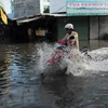 Nước ngập sâu trên đường phường Thạnh Lộc. (Ảnh: Mạnh Linh/TTXVN)