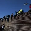 Người di cư vượt qua hàng rào biên giới giữa Mỹ và Mexico, gần cửa khẩu El Chaparral ở Tijuana, bang Baja California, Mexico. (Nguồn: AFP/TTXVN)