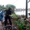 Cán bộ, chiến sỹ Bộ đội Biên phòng tỉnh Quảng Nam giúp đỡ người dân xã Tam An, huyện Phú Ninh, dọn dẹp vệ sinh môi trường sau mưa lụt. (Ảnh: Đỗ Trưởng/TTXVN)