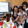 Các em học sinh cùng trải nghiệm công nghệ tại triển lãm. (Ảnh: Thu Hoài/TTXVN)