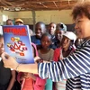 Phu nhân Đại sứ Việt Nam tại Nam Phi Trịnh Minh Hằng giới thiệu Báo Ảnh Việt Nam của TTXVN với trẻ em Lesotho. (Ảnh: Phi Hùng/TTXVN)