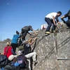 Người di cư Trung Mỹ vượt qua hàng rào biên giới Mỹ-Mexico ở Tijuana, bang Baja California, Mexico. (Nguồn: AFP/TTXVN)