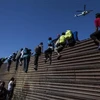 Người di cư Trung Mỹ tìm cách vượt qua hàng rào chắn tại khu vực biên giới ở Tijuana, bang Baja California (Mexico), trong hành trình tới Mỹ. (Nguồn: AFP/TTXVN)