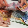 Kiểm tiền đô la New Zealand tại quầy giao dịch tiền tệ ở Auckland. (Nguồn: AFP/TTXVN)