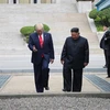 Tổng thống Mỹ Donald Trump (trái) và nhà lãnh đạo Triều Tiên Kim Jong-un bước chân qua đường ranh giới phân chia hai miền Triều Tiên tại DMZ, sang phần lãnh thổ của Triều Tiên chiều 30/6. (Nguồn: Yonhap/TTXVN)