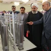 Người đứng đầu Tổ chức Năng lượng nguyên tử Iran (AEOI) Ali Akbar Salehi (phải) báo cáo với Tổng thống Iran Hassan Rouhani (thứ 2, trái) thăm quan một triển lãm nhân Ngày công nghệ hạt nhân ở Tehran. (Ảnh: AFP/TTXVN)