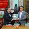Cựu Nhà báo Trần Tuấn tặng sách ảnh "Đại tướng Võ Nguyên Giáp trong lòng dân" cho người nhà gia đình Đại tướng và các đại biểu. (Ảnh: Thành Đạt/TTXVN)