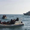 Lực lượng cứu hộ Anh (phía trước) chặn tàu chở người di cư từ Pháp băng qua eo biển Manche. (Ảnh: AFP/TTXVN)