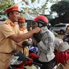 Cảnh sát giao thông Đắk Nông tuyên truyền pháp luật về trật tự an toàn giao thông, đồng thời đổi mũ bảo hiểm đạt chuẩn cho người dân. (Ảnh: TTXVN phát)