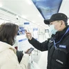 Nhân viên kiểm tra thân nhiệt của hành khách tại một nhà ga ở Vũ Hán, tỉnh Hồ Bắc, Trung Quốc. (Ảnh: THX/TTXVN)