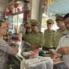 Lực lượng Quản lý thị trường tỉnh An Giang kiểm tra, nhắc nhở các hiệu thuốc tân dược ký cam kết không tăng giá bán khẩu trang y tế. (Ảnh: Công Mạo/TTXVN)