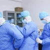 Các nhân viên y tế giúp đỡ nhau mặc quần áo bảo hộ tại khu vực cách ly điều trị cho bệnh nhân nhiễm virus corona của bệnh viện ở Chương Châu, tỉnh Phúc Kiến, Trung Quốc. (Ảnh: THX/TTXVN)