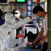 hân viên y tế kiểm tra thân nhiệt cho người dân tại thành phố Trạm Giang, tỉnh Quảng Đông, Trung Quốc. (Ảnh: THX/TTXVN)