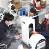 Các kỹ thuật viên kiểm tra robot khử trùng thế hệ đầu tiên tại công ty công nghệ Thanh Đảo, tỉnh Sơn Đông, Trung Quốc. (Ảnh: THX/TTXVN)