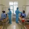 Các bác sỹ Trung tâm Y tế huyện Ân Thi đo thân nhiệt cho các em du học sinh. (Ảnh: Đinh Tuấn/TTXVN)