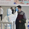 Nhân viên kiểm tra thân nhiệt của hành khách tại nhà ga tàu hỏa ở Vũ Hán, tỉnh Hồ Bắc, Trung Quốc. (Ảnh: THX/TTXVN)