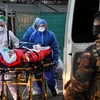 Nhân viên y tế chuyển bệnh nhân nhiễm COVID-19 lên xe cứu thương tới bệnh viện tại Mulhouse, miền đông nước Pháp. (Ảnh: AFP/TTXVN)