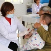 Cán bộ y tế tiêm phòng cho trẻ. (Ảnh: Nguyễn Lành/TTXVN)