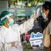 Nhân viên y tế kiểm tra thân nhiệt phòng lây nhiễm COVID-19 tại Bangkok,Thái Lan. (Ảnh: AFP/TTXVN)