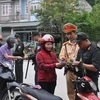 Lực lượng chức năng kiểm tra giấy phép lái xe, đăng ký xe đối với người điều khiển phương tiện xe môtô. (Ảnh: TTXVN phát)