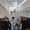 Tiếp viên hàng không mặc quần áo bảo hộ phòng lây nhiễm COVID-19 trên máy bay. (Ảnh: THX/TTXVN)