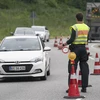Cảnh sát Đức điều khiển các phương tiện giao thông đi qua cửa khẩu Krusaa-Flensburg. (Ảnh: AFP/TTXVN)