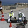 Các kỹ thuật viên từ công ty Kando trích xuất các mẫu nước thải từ một hố ga gần bãi biển ở thành phố Ashkelon. (Nguồn: AFP)