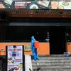 Nhân viên y tế phun thuốc tiêu độc khử trùng tại nhà hàng Pizza 106 Trần Thái Tông. (Ảnh: Thành Đạt/TTXVN)