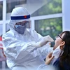 Nhân viên y tế lấy mẫu dịch hầu họng để xét nghiệm bằng phương pháp RT-PCR cho người dân trở về từ Đà Nẵng tại Nhà Hộ Sinh B - Trung Tâm Y Tế Quận Hai Bà Trưng. (Ảnh: Minh Quyết/TTXVN)