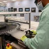 Kỹ thuật viên giám sát việc sản xuất quy mô lớn và cung ứng vắcxin phòng COVID-19. (Ảnh: AFP/TTXVN)