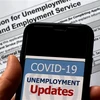 Cập nhật tình hình mất việc làm do dịch COVID-19 trên điện thoại tại Arlington, bang Virginia, Mỹ. (Ảnh: AFP/TTXVN)