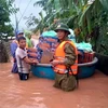 Ông Phan Thanh Miên (phải) dầm mưa, lội nước lũ cùng các đoàn cứu trợ đi cấp phát nhu yếu phẩm tiếp tế cho bà con trong đợt mưa lũ lịch sử vừa qua. (Ảnh: TTXVN phát)