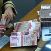 Kiểm đồng rupiah tại một trung tâm thu đổi ngoại tệ ở Jakarta. (Nguồn: Antara)