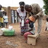 Nhân viên y tế cộng đồng giúp người dân uống thuốc phòng căn bệnh sốt rét tại Ouagadougou, Burkina Faso. (Ảnh: AFP/TTXVN)