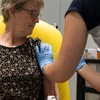 Nhân viên y tế tiêm thử nghiệm vắcxin ngừa COVID-19 cho người dân Anh. (Ảnh: AFP/TTXVN)